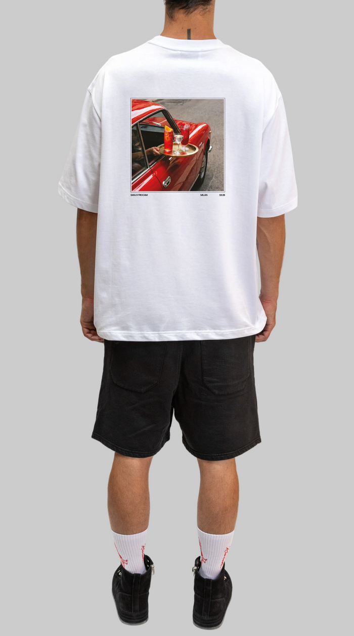 Person wearing a white t-shirt with a graphic of a red car on the back, standing against a white background.